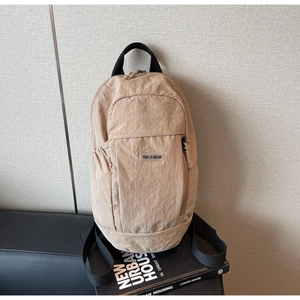 Detail of khaki crinkled nylon backpack with textile handles on a minimalist background