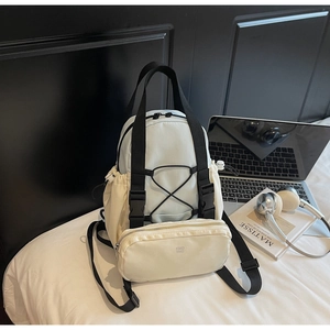 Detail of blue and beige functional backpack showing detachable pouch and elastic cords