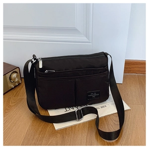 Detail of multi-layer zipper compartments on high-capacity black nylon crossbody bag