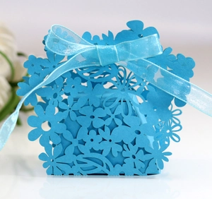 Detailed laser-cut floral patterns on a blue cardstock candy box with an organza ribbon bow