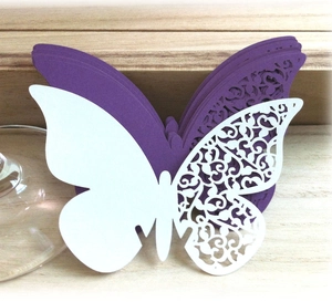 Detail of 3D laser-cut butterfly place cards in white and purple on a wood table
