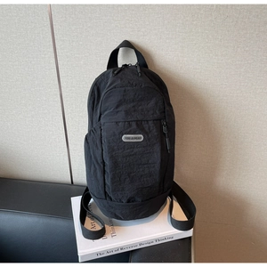 Close-up of black nylon backpack with silver brand label on a white prop book