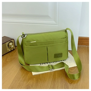 Detail of green nylon crossbody bag with multiple pockets and adjustable strap