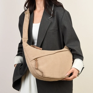 Detailed macro view of beige corduroy texture and woven zipper puller on crescent bag