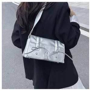 Silver metallic crossbody bag with bow details and wrinkled texture worn by model