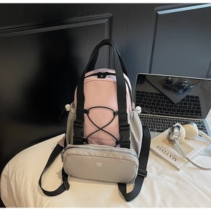 Pink and gray nylon backpack shown on a white bed with lifestyle props for a cozy vibe