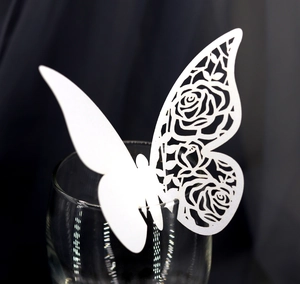 Détail d'un papillon en papier blanc découpé au laser avec motif de rose sur un verre