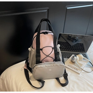 Detail view of pink and grey patchwork backpack with front pocket and elastic drawcord