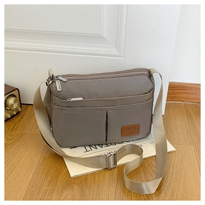 Detail of khaki nylon crossbody bag with multi-pocket design and adjustable strap