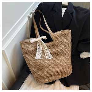 Detail of hand-woven straw tote bag with white lace bow and brown leather shoulder straps