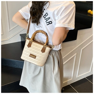 Sac bohème en paille avec poignée en bambou et garniture en cuir porté par un modèle
