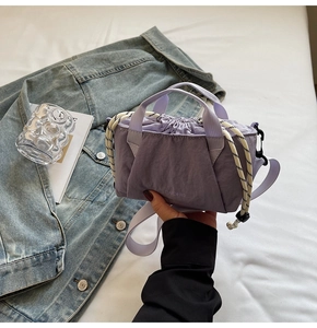 Close-up of a purple nylon drawstring bucket bag with pleated texture and rope detail
