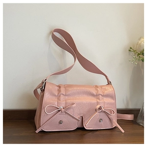 Detail of pink leather handbag featuring textured surface and decorative front bows