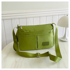 Close-up of avocado green canvas crossbody bag with multiple pockets and fabric brand label