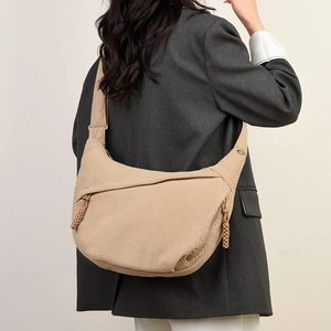 Close-up of khaki corduroy texture and braided zipper detail on the crescent bag