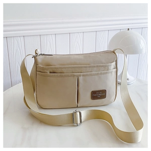Close-up of beige nylon crossbody bag with multi-pocket design and leather logo tag