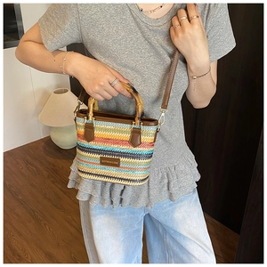 Détail du sac en paille à rayures colorées avec anses en bambou et bandoulière brune