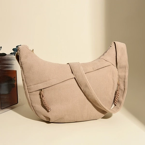 Detailed close-up of beige corduroy hobo bag showing ribbed texture and woven zipper puller