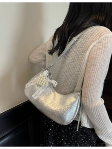 Silver crescent underarm bag with pearl heart and lace bow shown on model's shoulder