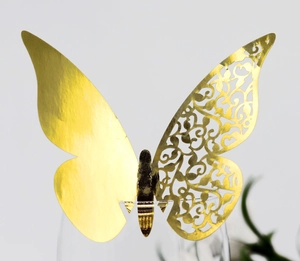 Close-up of golden laser-cut butterfly decoration with hollow pattern on glass rim