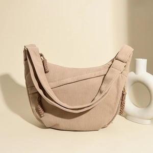 Detail of beige corduroy crescent bag showing striped texture and woven zipper pull