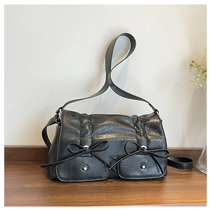 Detail of black vintage shoulder bag featuring pleat texture and leather bow accents