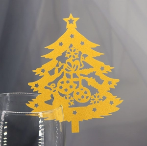 Close-up of golden laser-cut Christmas tree place card on the edge of a glass