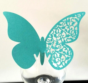 Detailed teal 3D butterfly place card with intricate laser-cut lace pattern on a glass