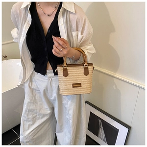 Détail du sac cabas en paille tissée avec poignée en bambou et base en cuir marron pour plage