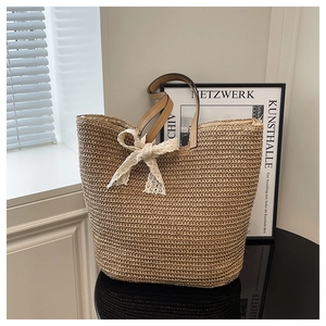 Close-up of woven straw tote bag featuring a decorative white lace bow and leather handles