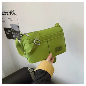 Detail of neon green nylon crossbody bag with multi-zipper pockets and wide strap