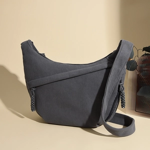 Macro detail of dark grey corduroy fabric texture and crescent shape on a crossbody bag
