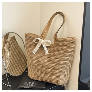 Detailed close-up of woven straw tote bag texture and white lace bow decoration
