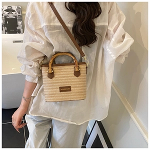 Détail du sac seau en paille tissée avec poignée en bambou et bandoulière en cuir brun