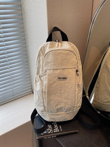 Minimalist beige nylon backpack with functional pleated texture and dual zipper pockets