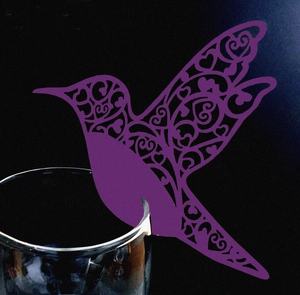 Detail of purple laser-cut hummingbird paper card with heart patterns on wine glass