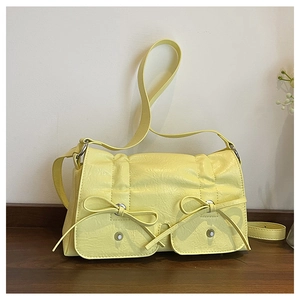 Close-up of light yellow pleated bag featuring cute bow pockets and long shoulder strap