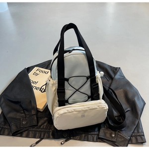 Detail view of the light blue backpack with KMD 2ND pouch on a leather jacket background