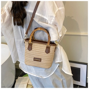 Détail d'un sac bohème en paille avec anses en bambou et finitions cuir sur un mannequin