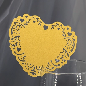 Macro detail of laser-cut heart place card with golden glitter finish on a glass rim