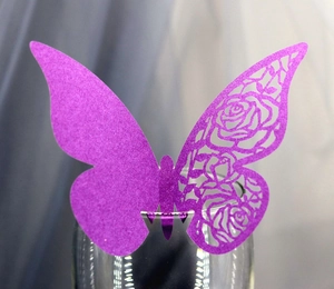 Détail du marque-place papillon violet découpé au laser avec motifs de roses sur verre