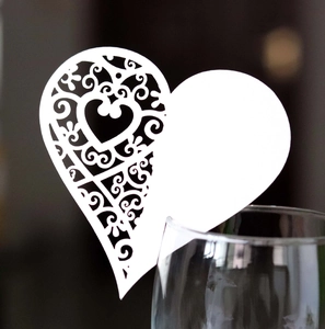 Elegant white laser-cut heart place card on glass for wedding and banquet table decor
