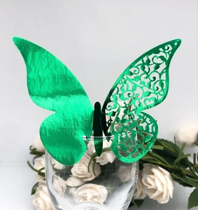 Detail of laser-cut green butterfly place card on wine glass with floral background