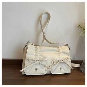 Detail of cream white faux leather bag featuring pleated texture and bow accents
