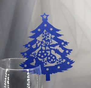 Macro shot of blue laser-cut Christmas tree place card on a wine glass rim