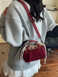 Burgundy canvas bucket bag with drawstring closure and adjustable woven shoulder strap