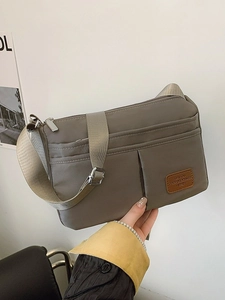 Neutral khaki nylon crossbody bag with wide strap and multiple pockets for daily commuting