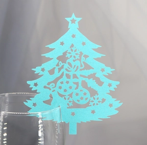 Close-up of light blue laser-cut Christmas tree place card on wine glass rim