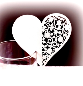 Detail of laser-cut heart-shaped place card with intricate patterns for wine glasses