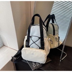 Detail view of cream backpack with black straps and detachable small pouch on books